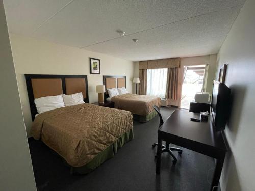 a hotel room with two beds and a desk at Heritage Inn & Suites in Niagara Falls