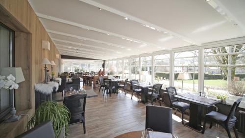 a restaurant with tables and chairs and windows at Auberge la Hutte Lurette in Paliseul