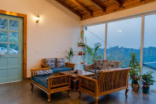 a living room with chairs and a table and a window at Shivoham Himalayan Resort in Almora