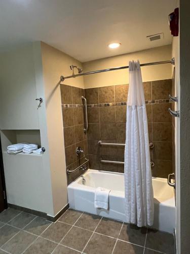 a bathroom with a tub and a shower with a shower curtain at HomeTowne Studios & Suites by Red Roof Washington in Washington