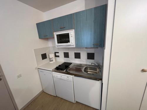 Elle comprend une petite cuisine avec des placards bleus et un four micro-ondes. dans l'établissement Bel Appartement en rez de chaussée, à Cauterets
