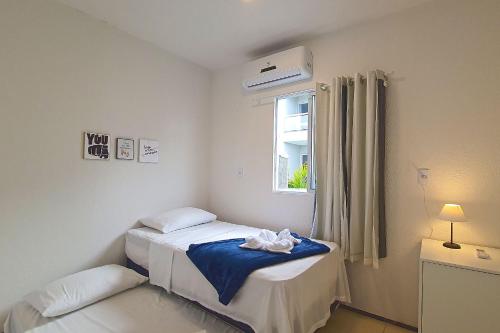 een kleine slaapkamer met 2 bedden en een raam bij Beach Townhouses #105 - Praticidade por Carpediem in Aquiraz