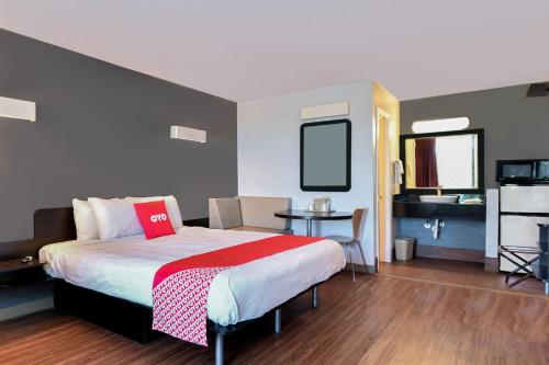 Schlafzimmer mit einem Bett, einem Tisch und einem TV in der Unterkunft OYO Hotel Valdosta GA I-75 in Valdosta