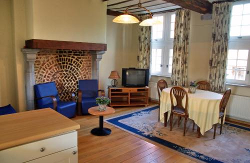 een woonkamer met een tafel en een open haard bij Vakantiewoningen-Pizzeria Blanckthys Voeren in Voeren
