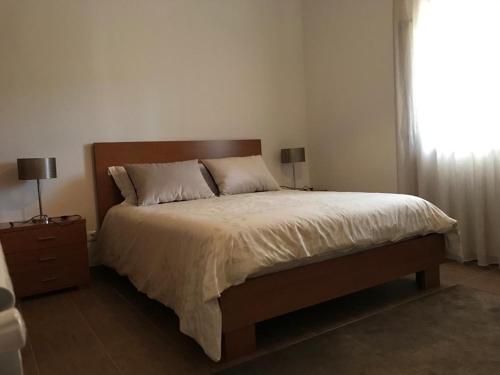 a bedroom with a bed with two lamps and a window at Moradia Gémea em Herdade Santa Marta in Zebreira