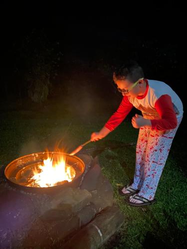 a young boy is standing next to a fire at Cabaña rodeada de naturaleza en San Carlos in Quesada