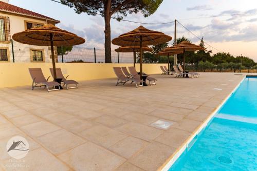 eine Terrasse mit Stühlen und Sonnenschirmen neben einem Pool in der Unterkunft Moradia Gémea em Herdade Santa Marta in Zebreira