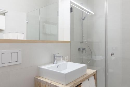 a white bathroom with a sink and a shower at Randolins Familienresort in St. Moritz