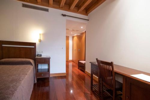 a bedroom with a bed and a desk with a desk at San Francisco Hotel Monumento in Santiago de Compostela