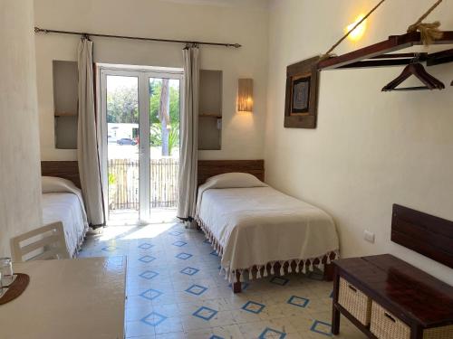 a bedroom with two beds and a door to a patio at Hotel La Piazzetta in Mérida