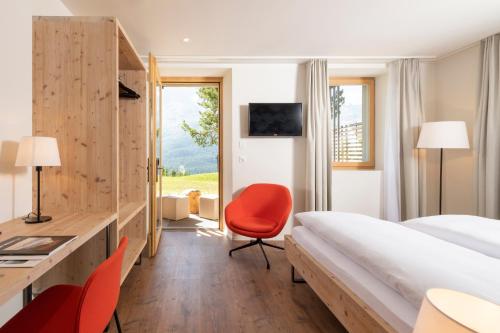 a hotel room with a bed and a desk and a chair at Randolins Familienresort in St. Moritz