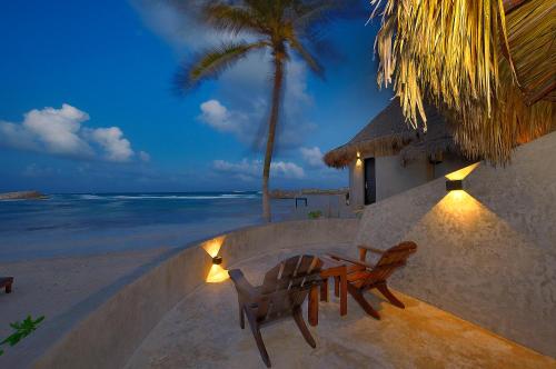 two chairs and a table on the beach at night at Maya Tulum By G Hotels in Tulum