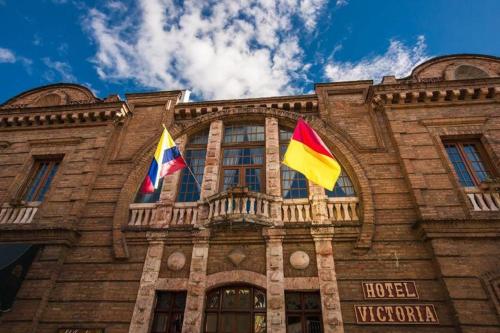 two flags flying in front of a building at Hotel Victoria in Cuenca