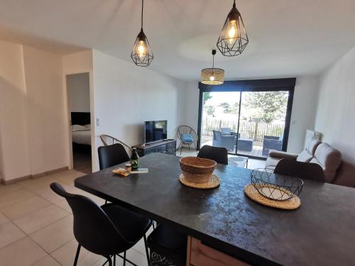 uma cozinha e sala de estar com mesa e cadeiras em Les Ganivelles em Donville-les-Bains