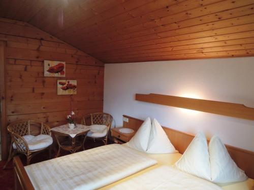 フラッハウにあるHaus Carinaのベッド2台、テーブル、椅子が備わる客室です。