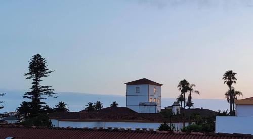 a clock tower on top of a building with palm trees at Atlantic Town 2 - Free Parking in Ponta Delgada
