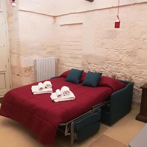 a bedroom with a red bed with towels on it at Trulli Manuela 2 in Locorotondo