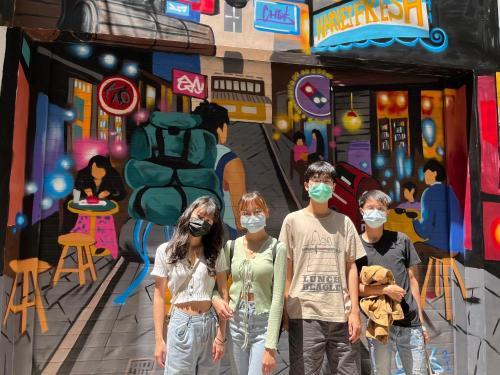 a group of people wearing face masks in front of a painting at mydeer backpacker in Tainan