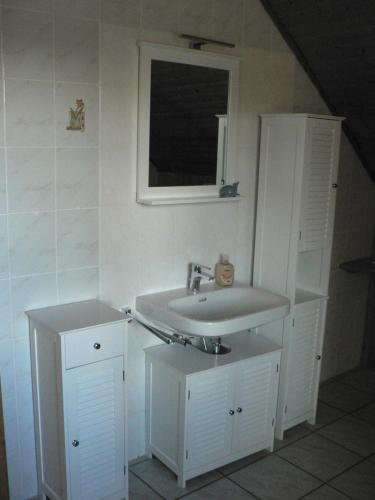 a white bathroom with a sink and a window at Ferienwohnungen Torfweg in Weddingstedt