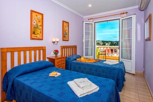 a bedroom with two blue beds and a balcony at Villa Dolores by Villa Plus in Cala Galdana