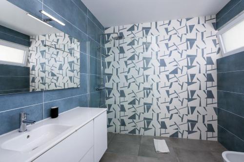 een badkamer met een witte wastafel en blauwe tegels bij Villa Dona Julia by Villa Plus in Carvoeiro