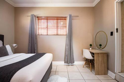 a bedroom with a bed and a mirror and a window at Beautiful and Modern apartment close to Menlyn in Pretoria