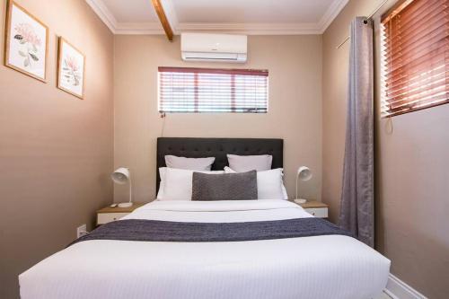 a bedroom with a large white bed with two lamps at Beautiful and Modern apartment close to Menlyn in Pretoria