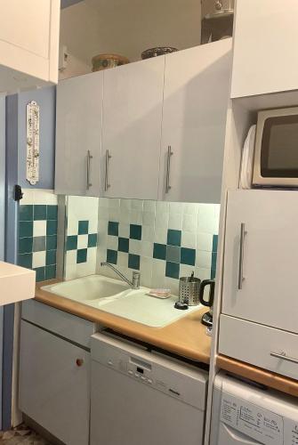 une cuisine avec des armoires blanches et un évier dans l'établissement Saint-Jean-de-Luz-location 2 minutes a pieds de la plage, à Saint-Jean-de-Luz