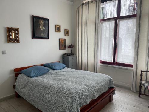 une chambre avec un lit avec des oreillers bleus et une fenêtre dans l'établissement Saint-Jean-de-Luz-location 2 minutes a pieds de la plage, à Saint-Jean-de-Luz