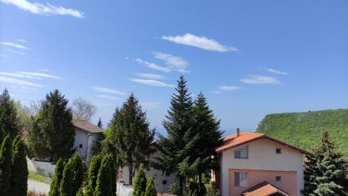 a house with trees and a hill in the background at Jeni's apartment in Kavarna
