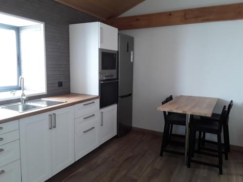 a kitchen with white cabinets and a table with a sink at Casa Xavier in Ponta Delgada