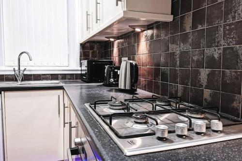 a kitchen with a stove top oven in a kitchen at Glasgow Southside: Cosy 2 Bedroom Apartment in Glasgow