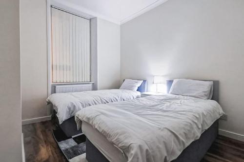 two beds in a white room with a window at Glasgow Southside: Cosy 2 Bedroom Apartment in Glasgow