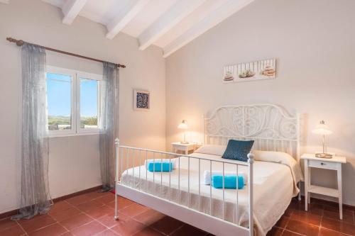 a bedroom with a bed with blue pillows and a window at Villa Son Muscart by Villa Plus in Es Mercadal
