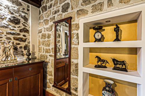 a room with a stone wall with shelves and a mirror at Heritage Hotel & Estate Raznjevica Dvori AD 1307 in Polača
