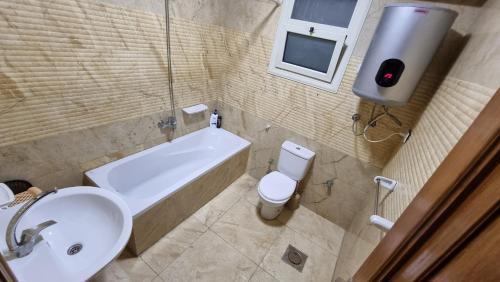 a bathroom with a sink and a toilet and a bath tub at Alex sea view apartment - families only in Alexandria