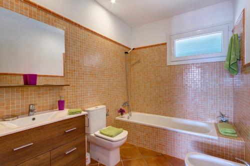 Un baño con inodoro, bañera y lavabo. en Villa Torrenova by Villa Plus, en Alaior