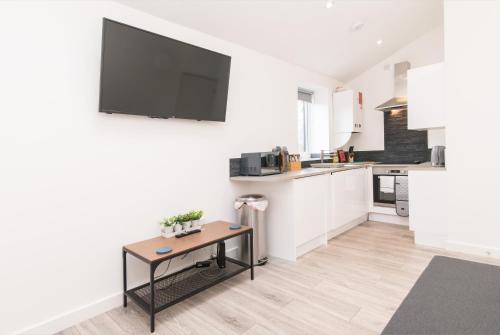 a kitchen with a table and a tv on the wall at Cricket View - Fabulous 1bed Apt near Trent Bridge Cricket Ground in Nottingham