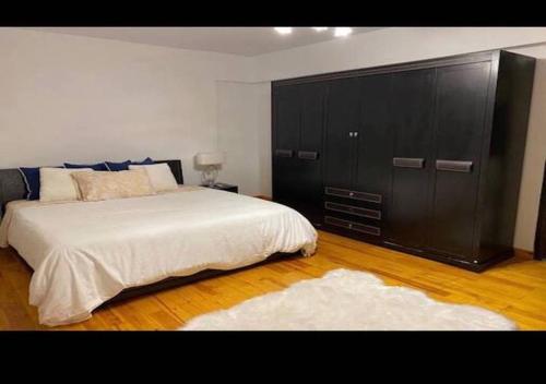 ein Schlafzimmer mit einem großen Bett und einem schwarzen Schrank in der Unterkunft Luxurious and Modern 3 Bedroom Maadi Apartment in Kairo