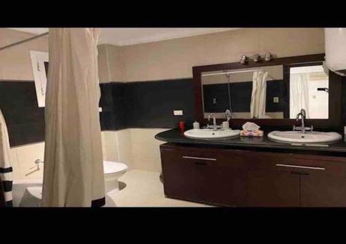 a bathroom with two sinks and a toilet and a mirror at Luxurious and Modern 3 Bedroom Maadi Apartment in Cairo