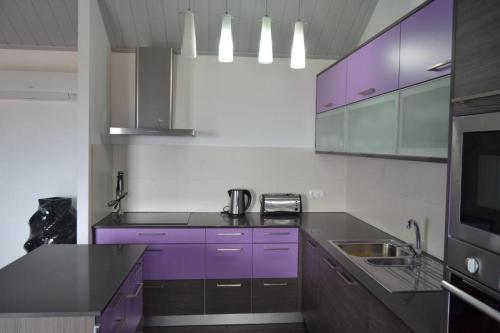 a kitchen with purple cabinets and a sink at Casa da Pedra in Horta