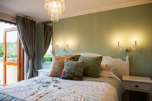 Un dormitorio con una cama con paredes verdes y una lámpara de araña. en Strawberry Fields Country Manor Guest House, en Johannesburgo