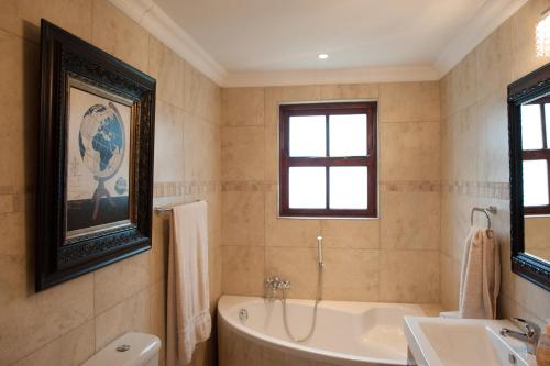 La salle de bains est pourvue d'une baignoire et d'un lavabo. dans l'établissement Strawberry Fields Country Manor Guest House, à Johannesbourg