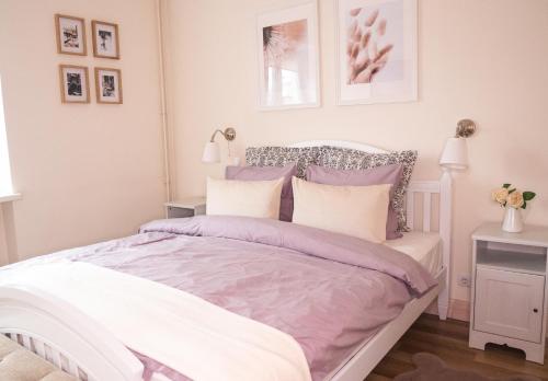 1 dormitorio con 1 cama con almohadas moradas y blancas en Provance Apartment, en Liepāja