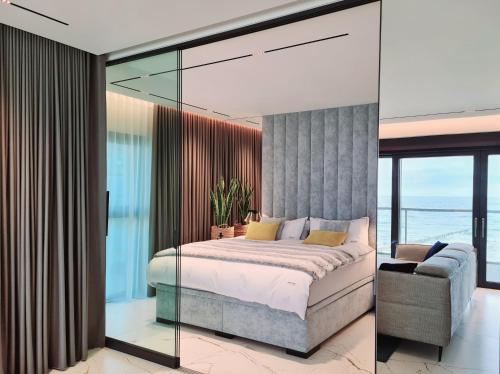 a bedroom with a bed and a glass wall at BALTIC VIEW Luxury Apartment Gardenia FRONT in Dziwnów