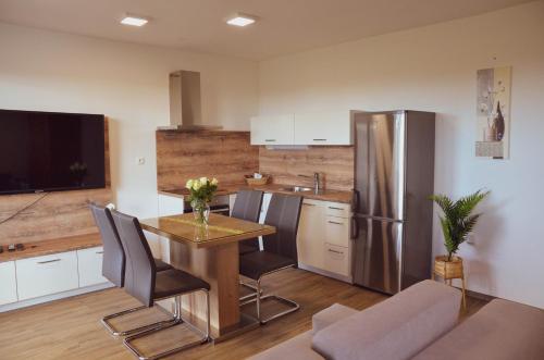 eine Küche mit einem Tisch und einem Kühlschrank aus Edelstahl in der Unterkunft Apartmaji Aida in Moravske-Toplice