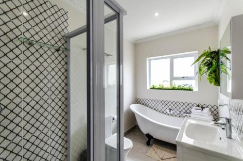 a bathroom with a tub and a toilet and a sink at The Holy Hill Royal Alfred Marina in Port Alfred