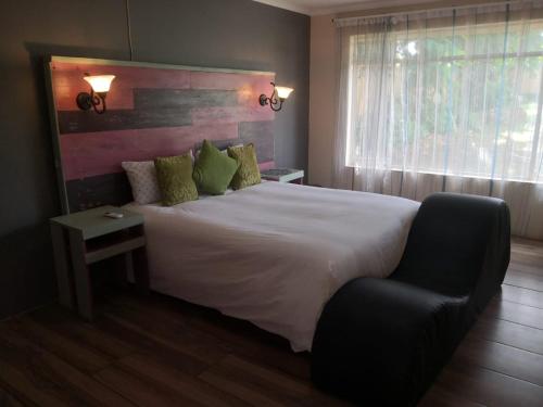 a bedroom with a large white bed and a chair at 15 On Reitz Bela bela in Bela-Bela