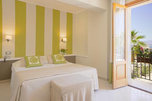 una camera da letto con letto a righe verdi e bianche di Hotel Al Madarig a Castellammare del Golfo