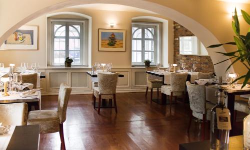 a dining room with tables and chairs and windows at Villa Patriot Boutique Hotel in Mariánské Lázně